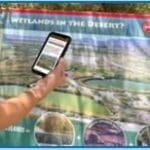 A woman holding up a map of wetlands in the desert.
