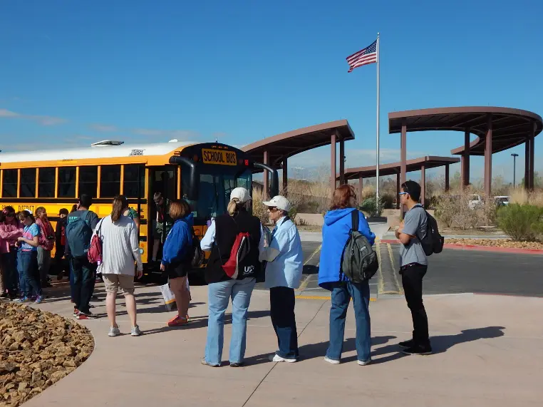 A group of people standing in front of a school bus.