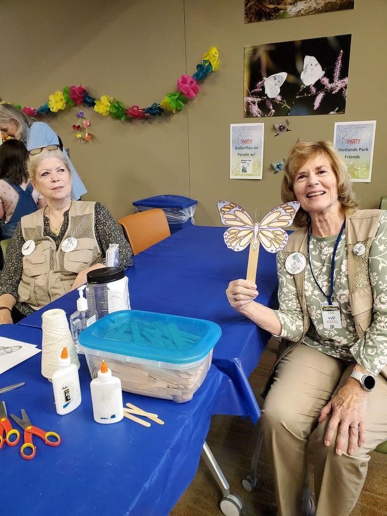 Two women crafting butterflies at a party.