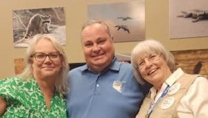 Three people smiling in a room.