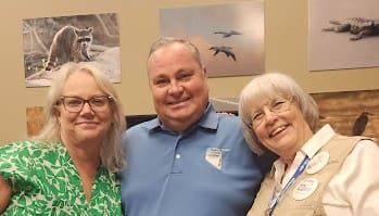Three people smiling in a room.