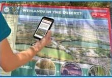 A woman holding up a map of wetlands in the desert.