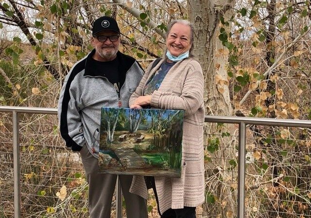 Betty Jones holding a painting and smiling