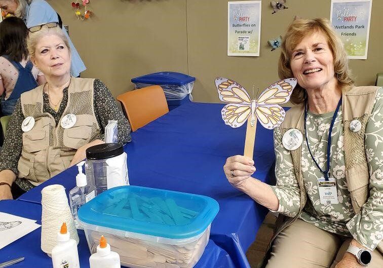 Two women crafting butterflies at a party.