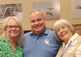 Three people smiling in a room.